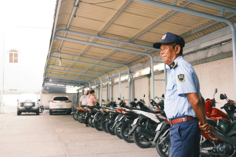 man standing in the shade with several motorcycles