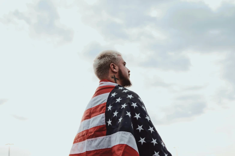 a man in black jacket standing with american flag cape around his neck