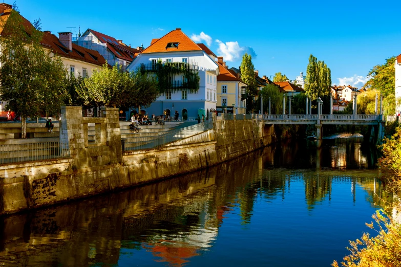 a river with buildings surrounding it, next to an old bridge