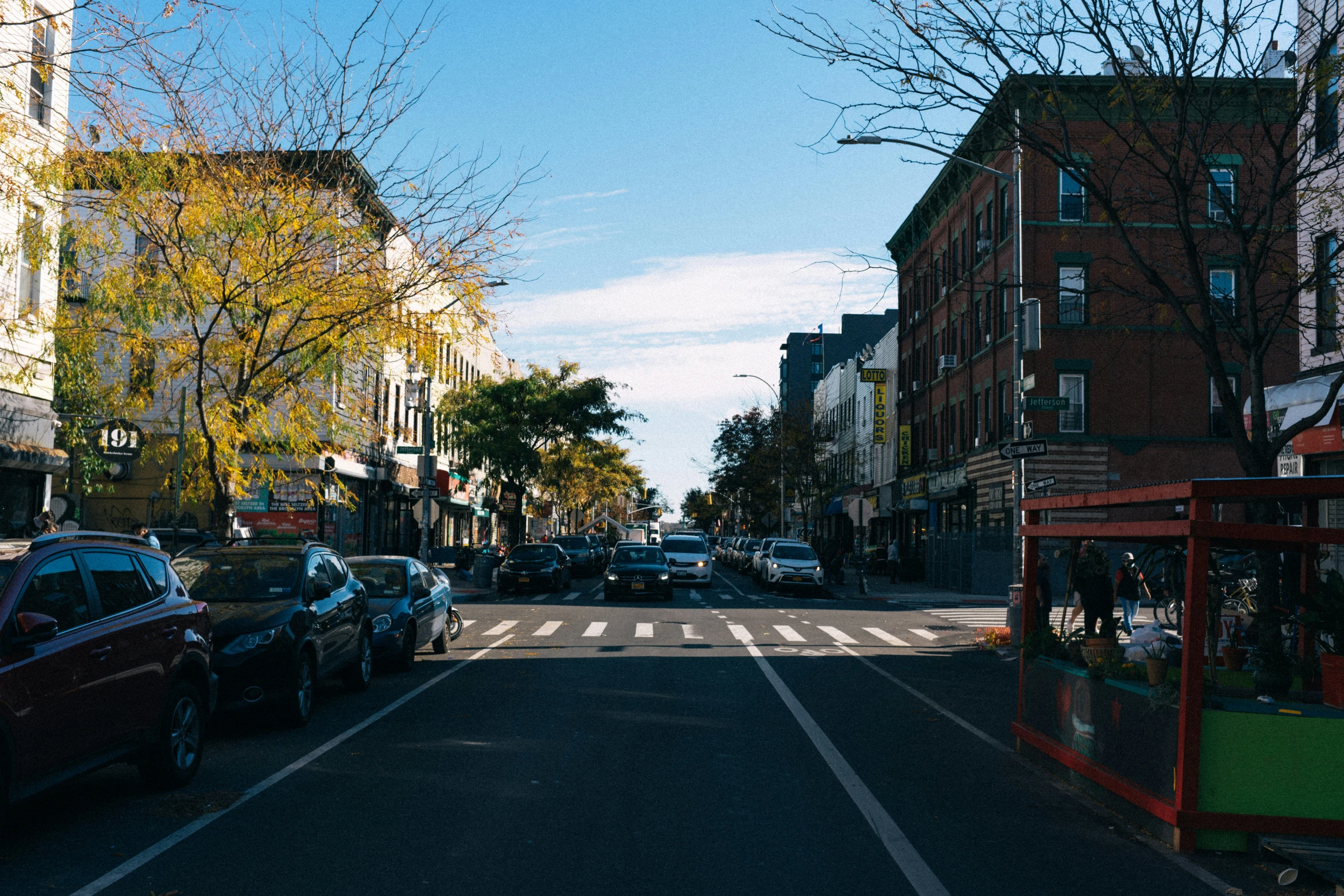 several parked cars and pedestrians on the street