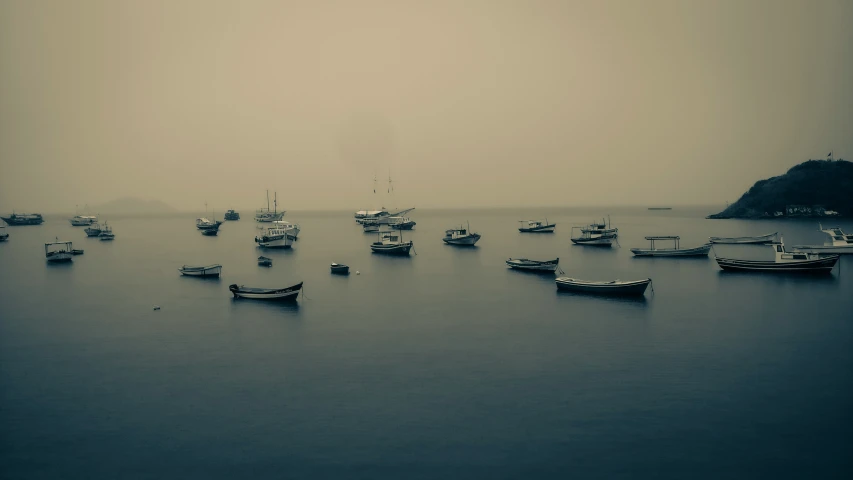 boats are sitting in a calm harbor surrounded by fog