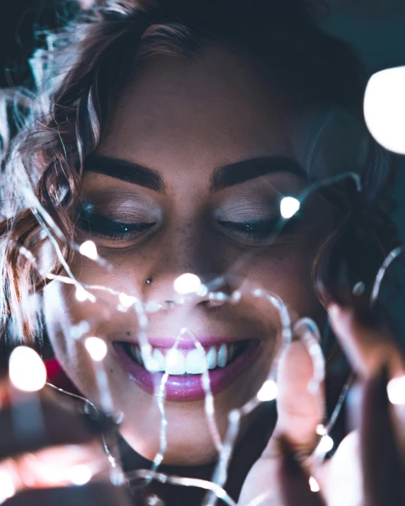 a close - up po of a smiling woman holding light bulbs