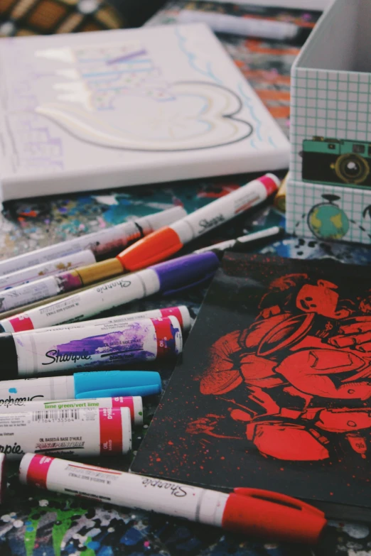 several markers and books are displayed next to a notebook