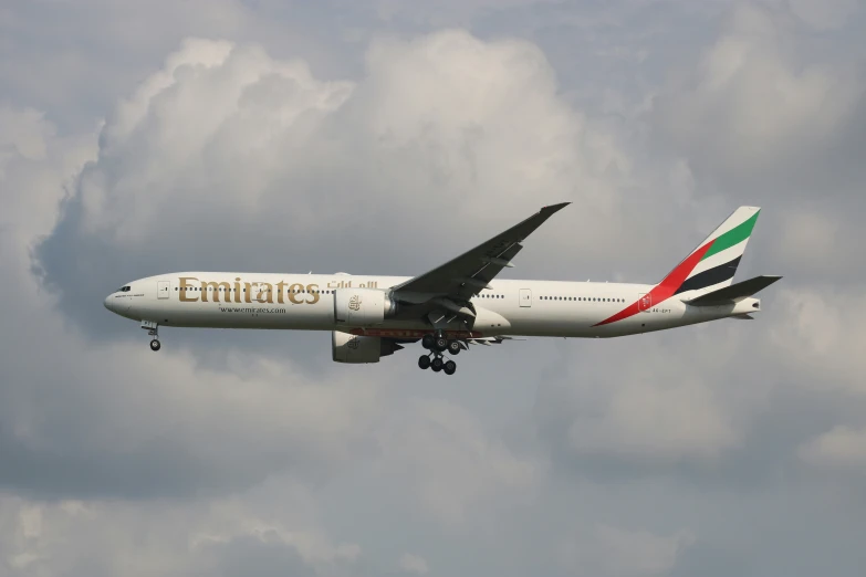 an emirates airline jet flies through the cloudy sky