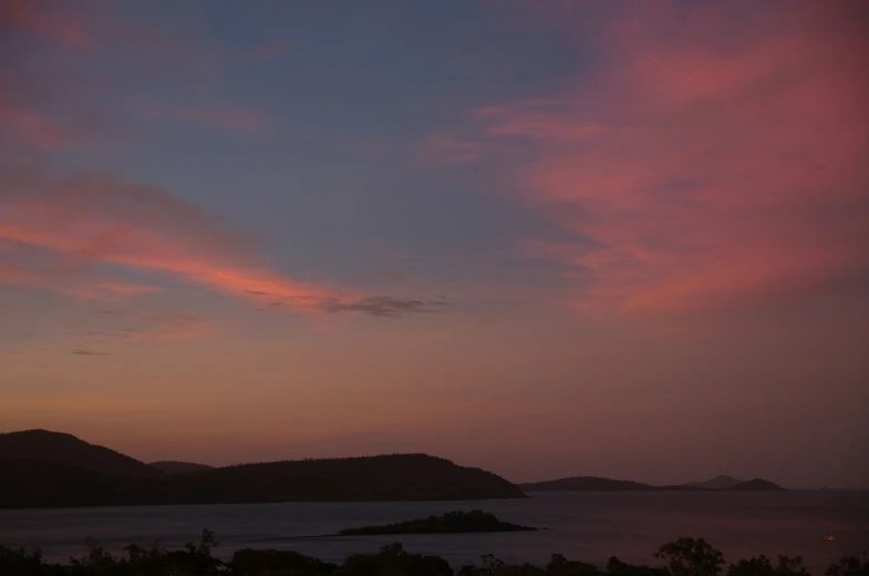 a dark sky with many clouds and land, with water and some hills