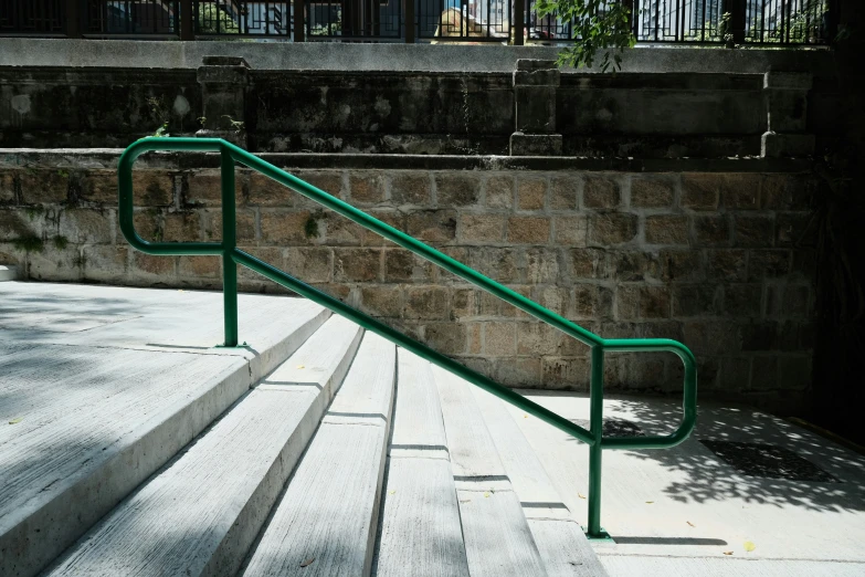 green metal railing next to stone stairs and tree