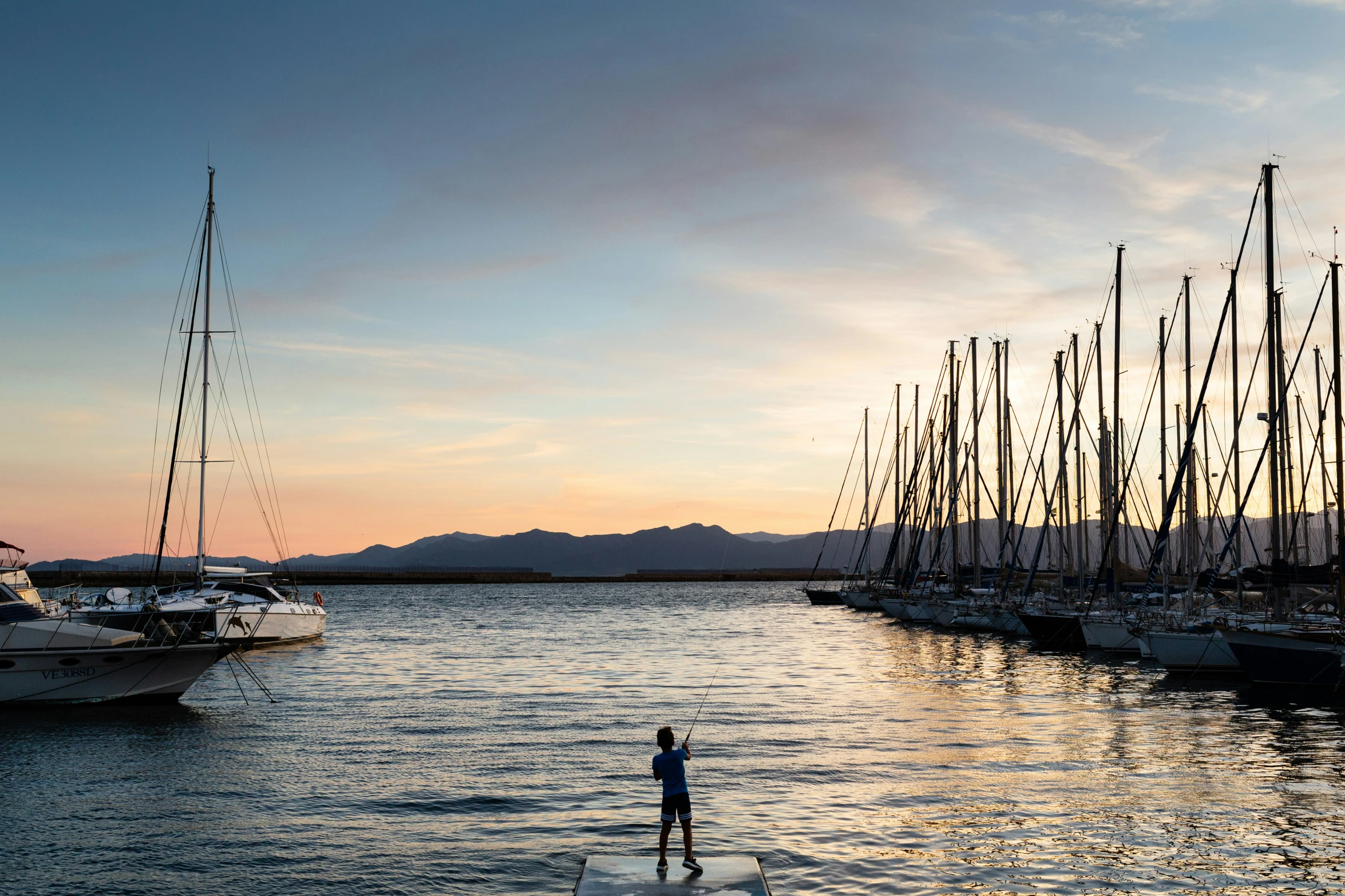 a boat on the water and some tall boats at sunset