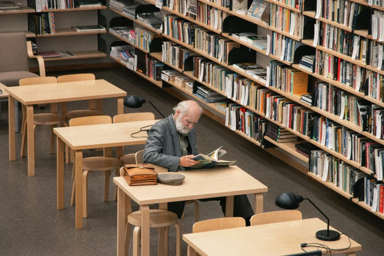 a man sitting at a table in a liry with a lot of books