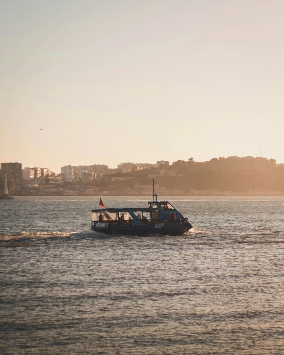 a boat sails through the ocean with a city in the background