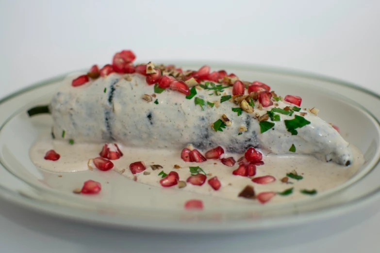 a white plate holding food with red pomegranate on top of it