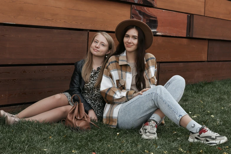 two women sitting side by side in front of a building