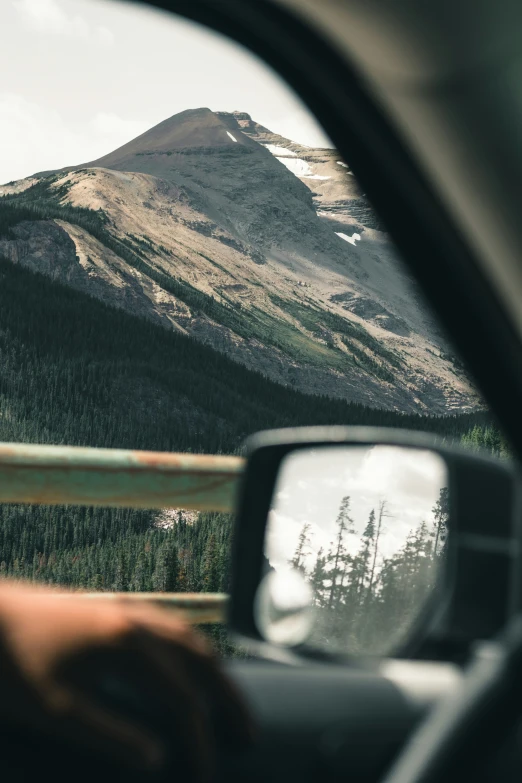 a side view mirror in a vehicle looking at a mountain