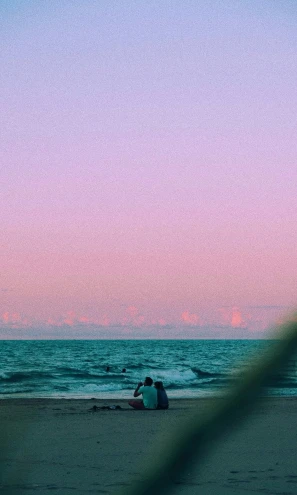 couple sitting on the beach watching the sunset