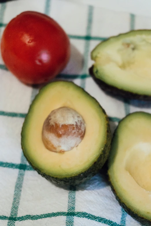 an avocado, tomato and some other food on a table