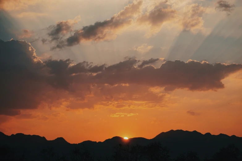 a person flying a kite over mountains and trees at sunset