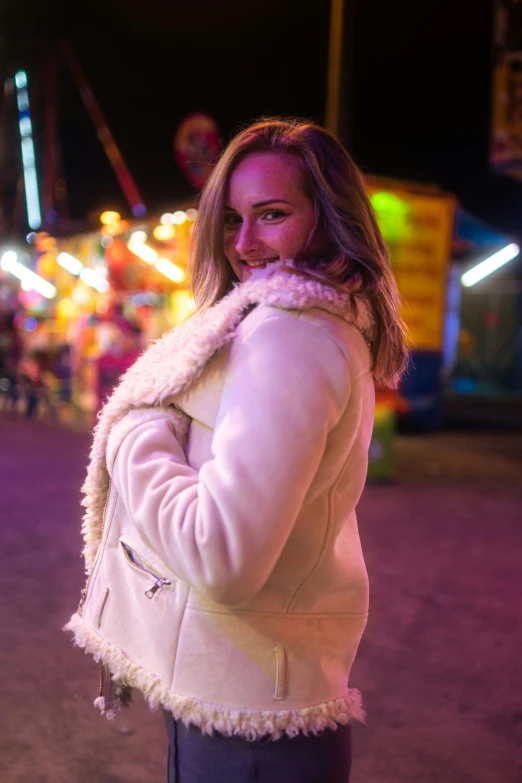 a woman wearing a white coat with her back turned at night