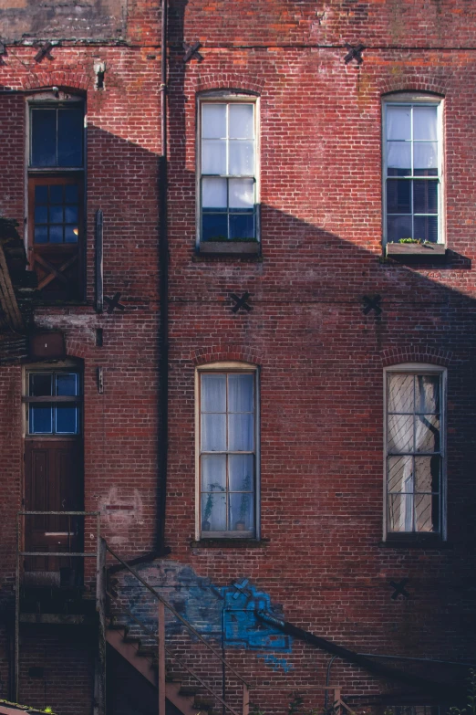 two windows in a brick building on the side of the street