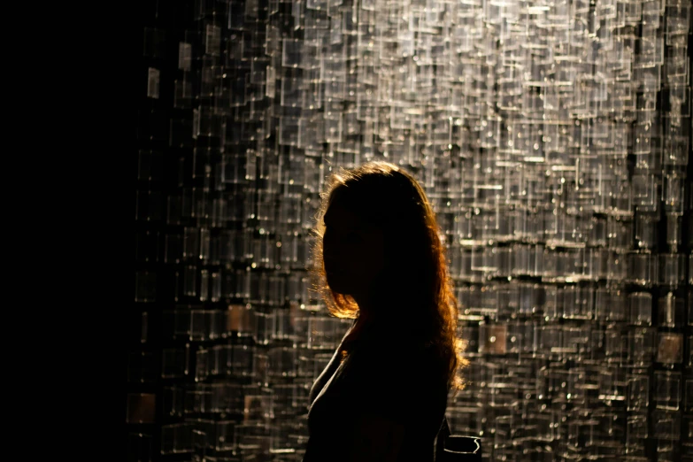 a woman is silhouetted in front of an artistic wall of rain