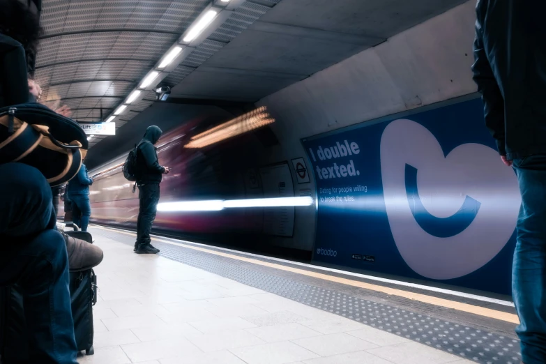 a train coming down the tracks with people standing beside