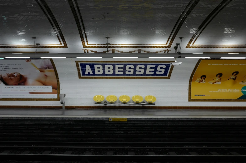 an empty subway station with posters on the wall