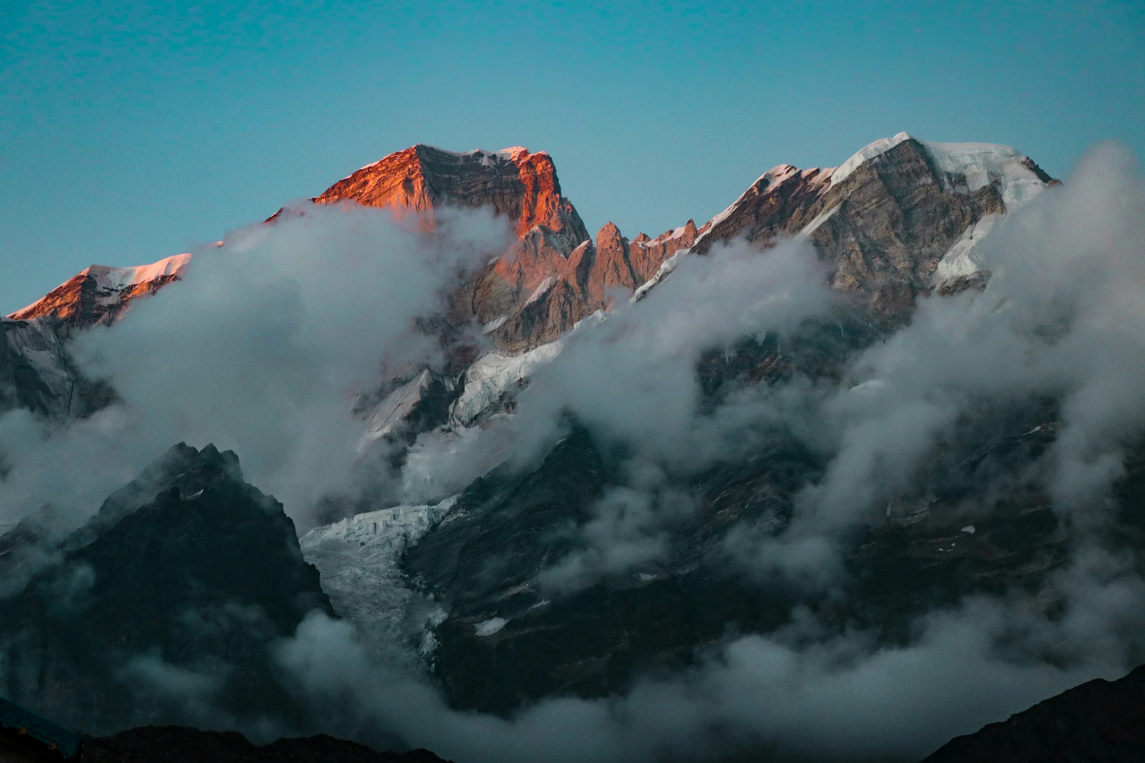 the peak of a large mountain with some clouds