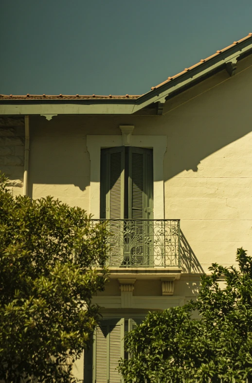 a small balcony with bushes surrounding it on a sunny day