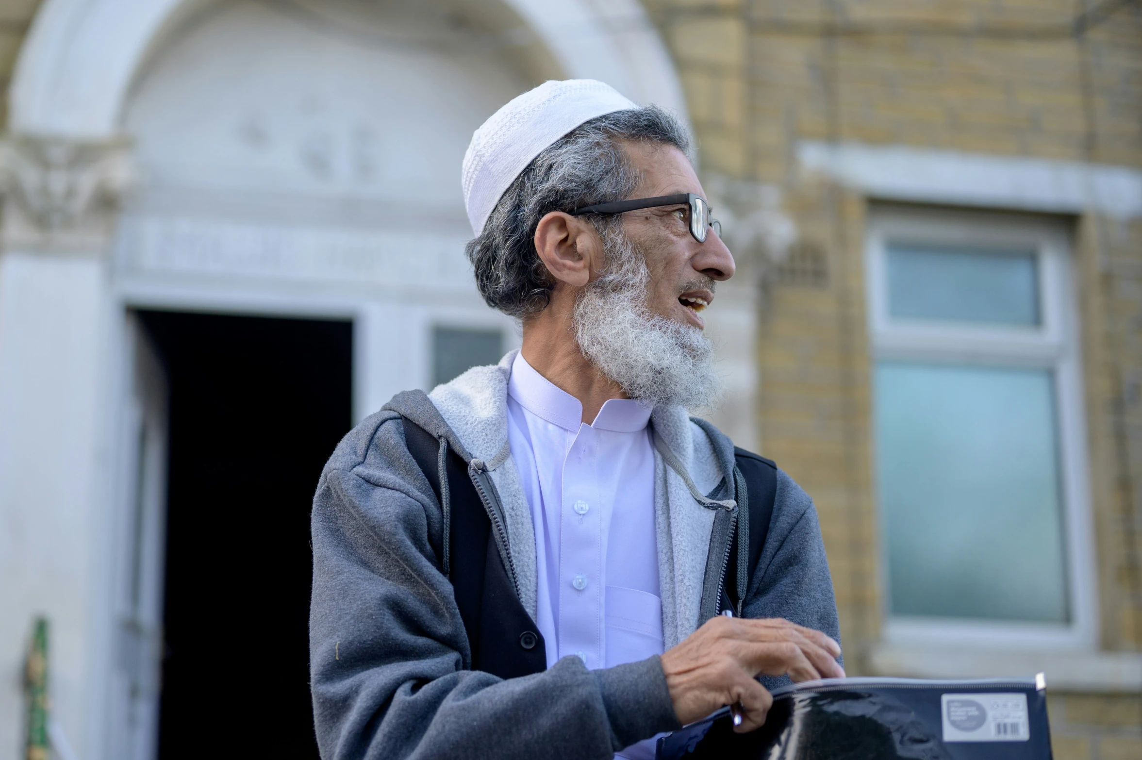 an old man in glasses, standing on the street