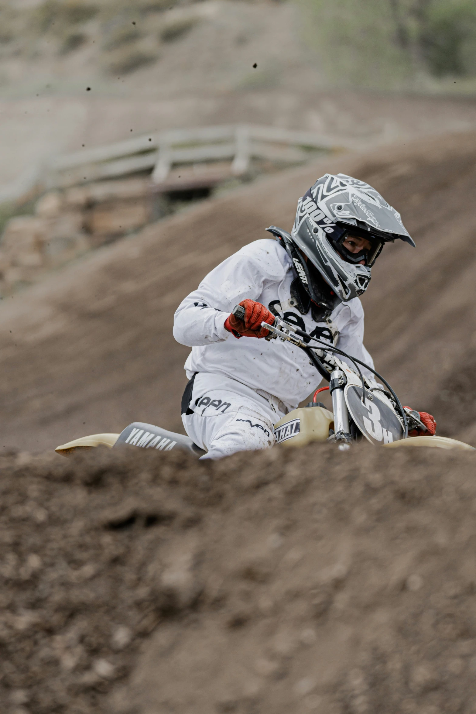 a motorcycle rider in white suit and helmet is riding on dirt