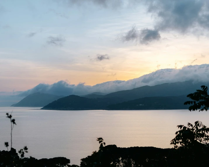 a body of water surrounded by mountains and clouds