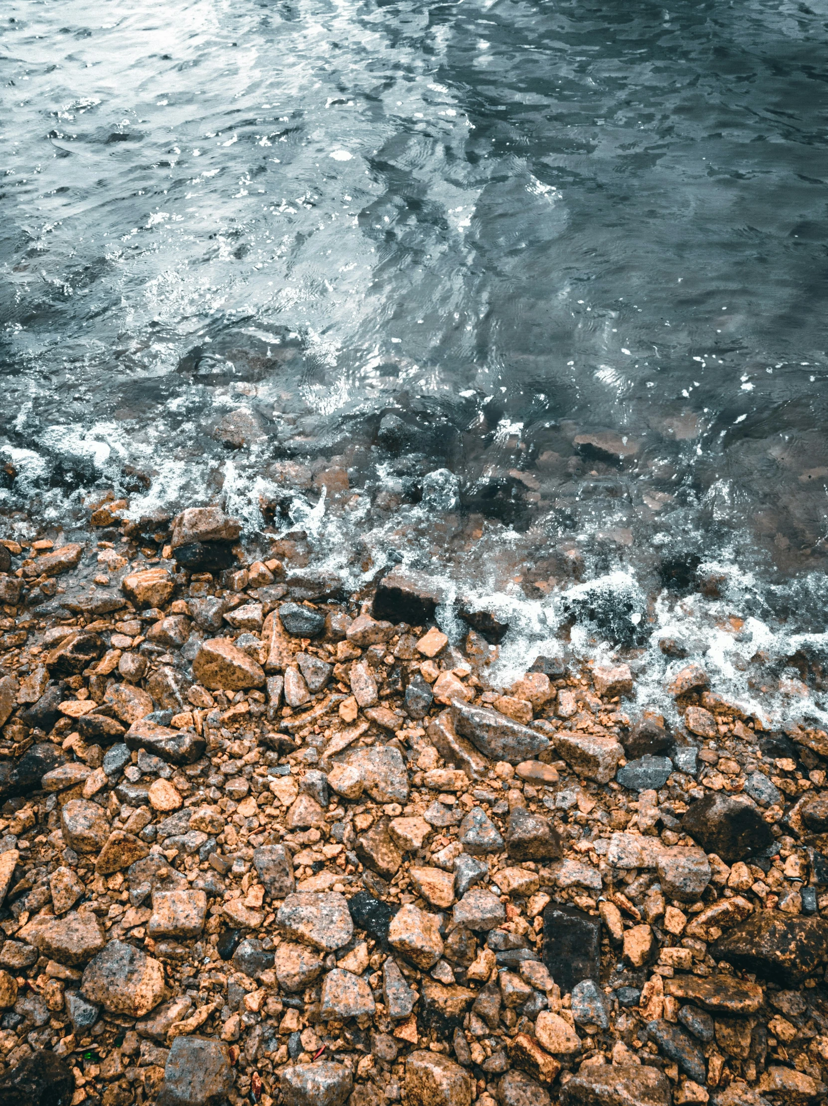 an ocean with stones and rocks on the shore