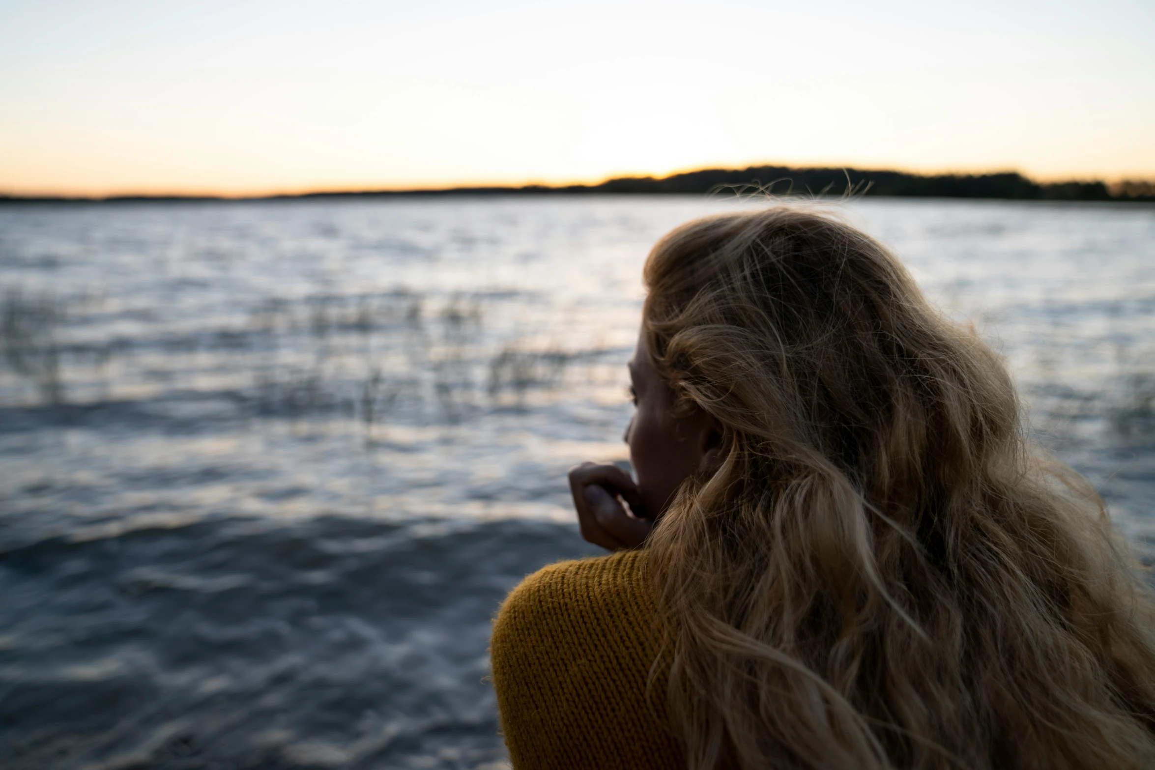 a woman stands in front of the water on a pier