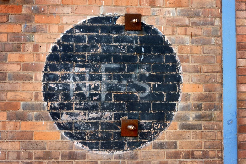 a painting that is in the shape of a round on a brick wall