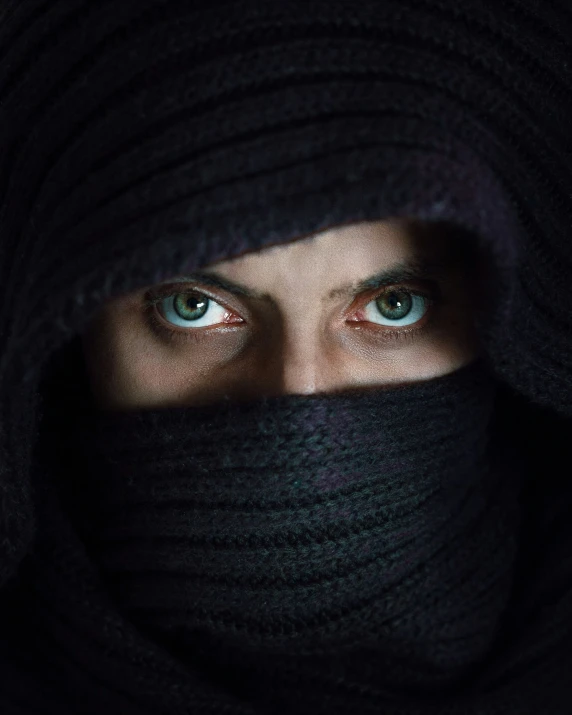 a woman wearing a scarf and staring at the camera