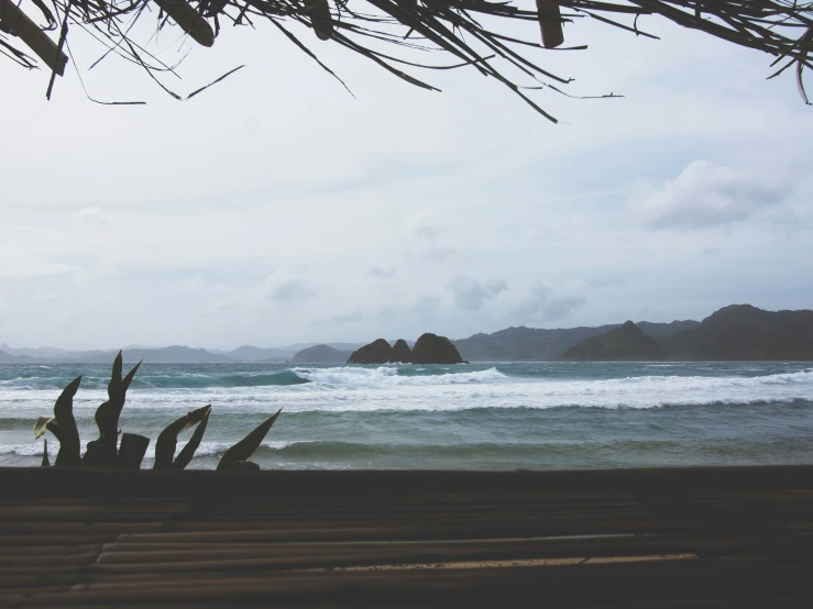 a bench sits next to the ocean with a few rocks in the distance