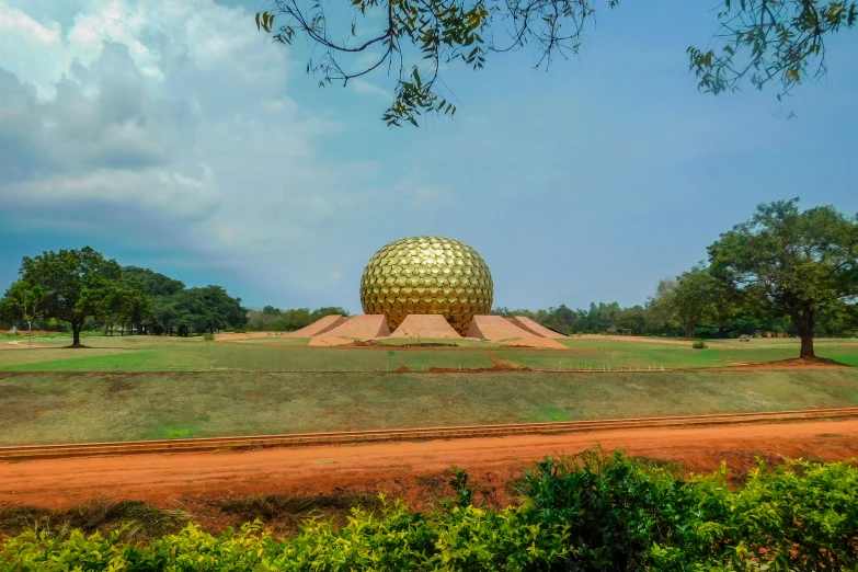 a large gold sculpture in the middle of a green field