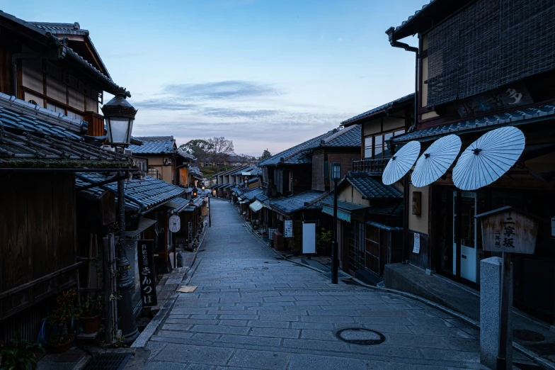 a sidewalk next to wooden buildings with umbrellas on top of them