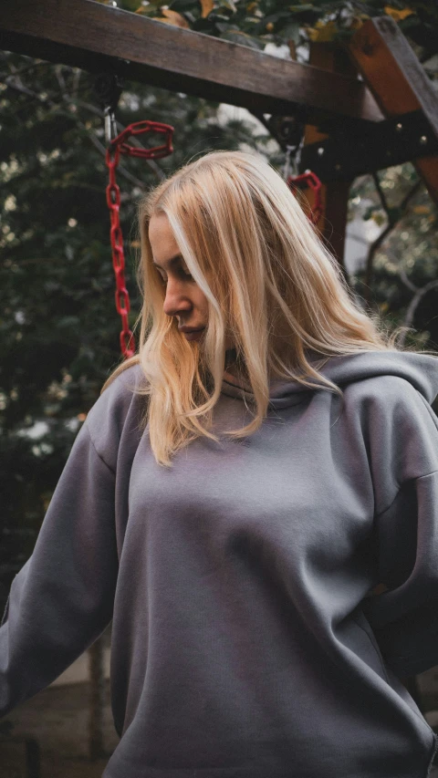 a woman is standing in the woods wearing a hoodie