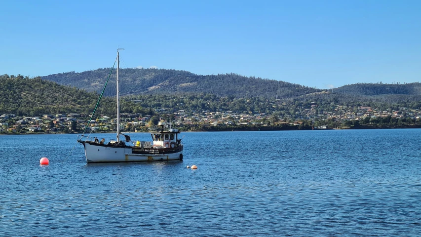 a fishing boat on water with hills and houses in background