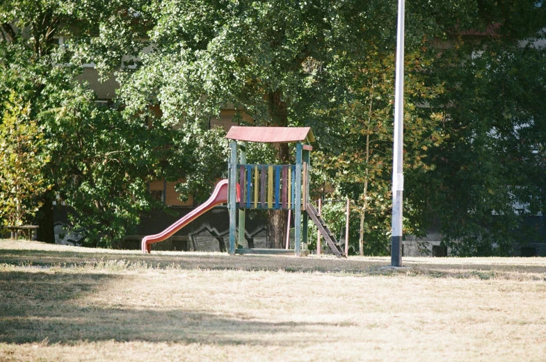a park with a play structure and some trees in the background