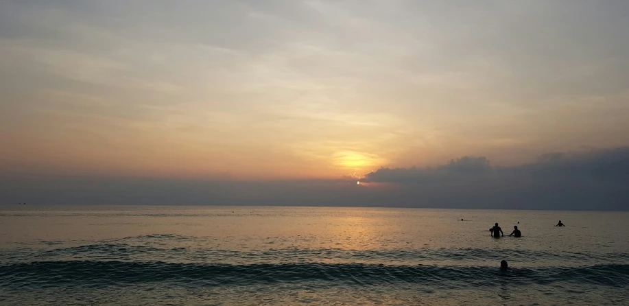 a couple of people floating in the ocean during the sunset