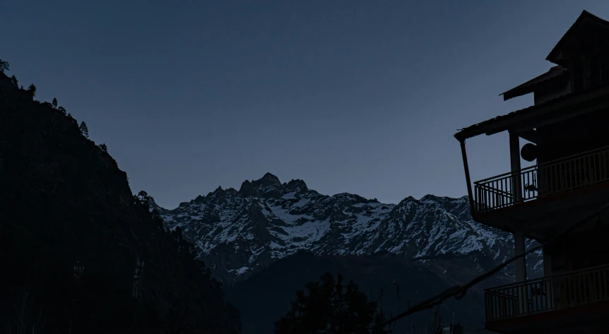 a house is on a dark mountain near a tall tree