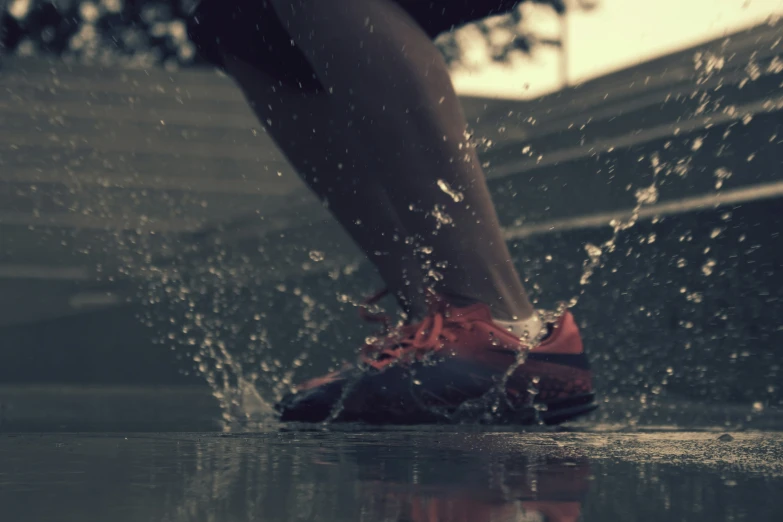 the legs and shoes of a runner splashing water onto their feet