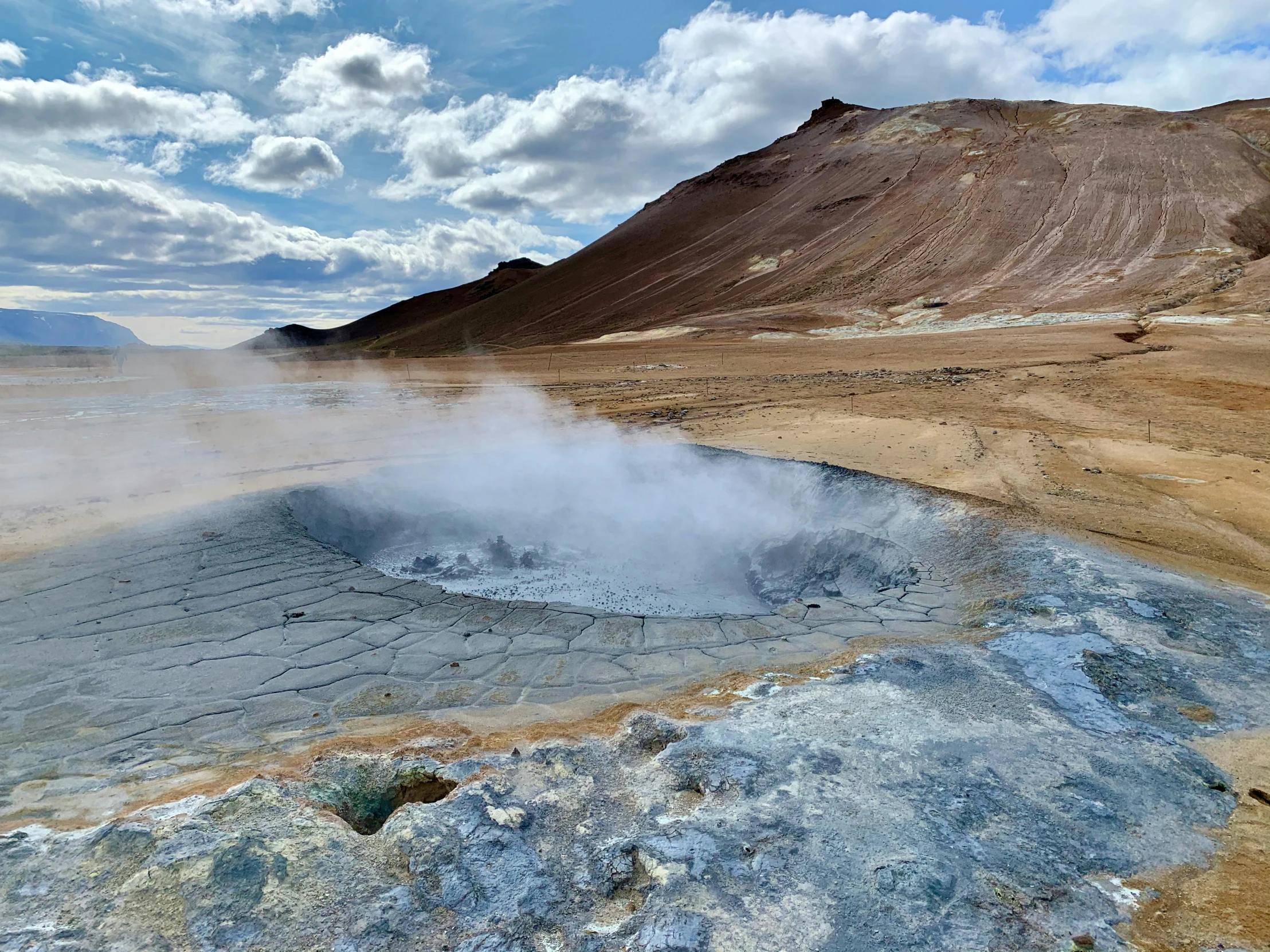 an icy mountain pool with steam rising from the ground