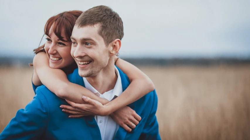 a couple holding each other in front of a field