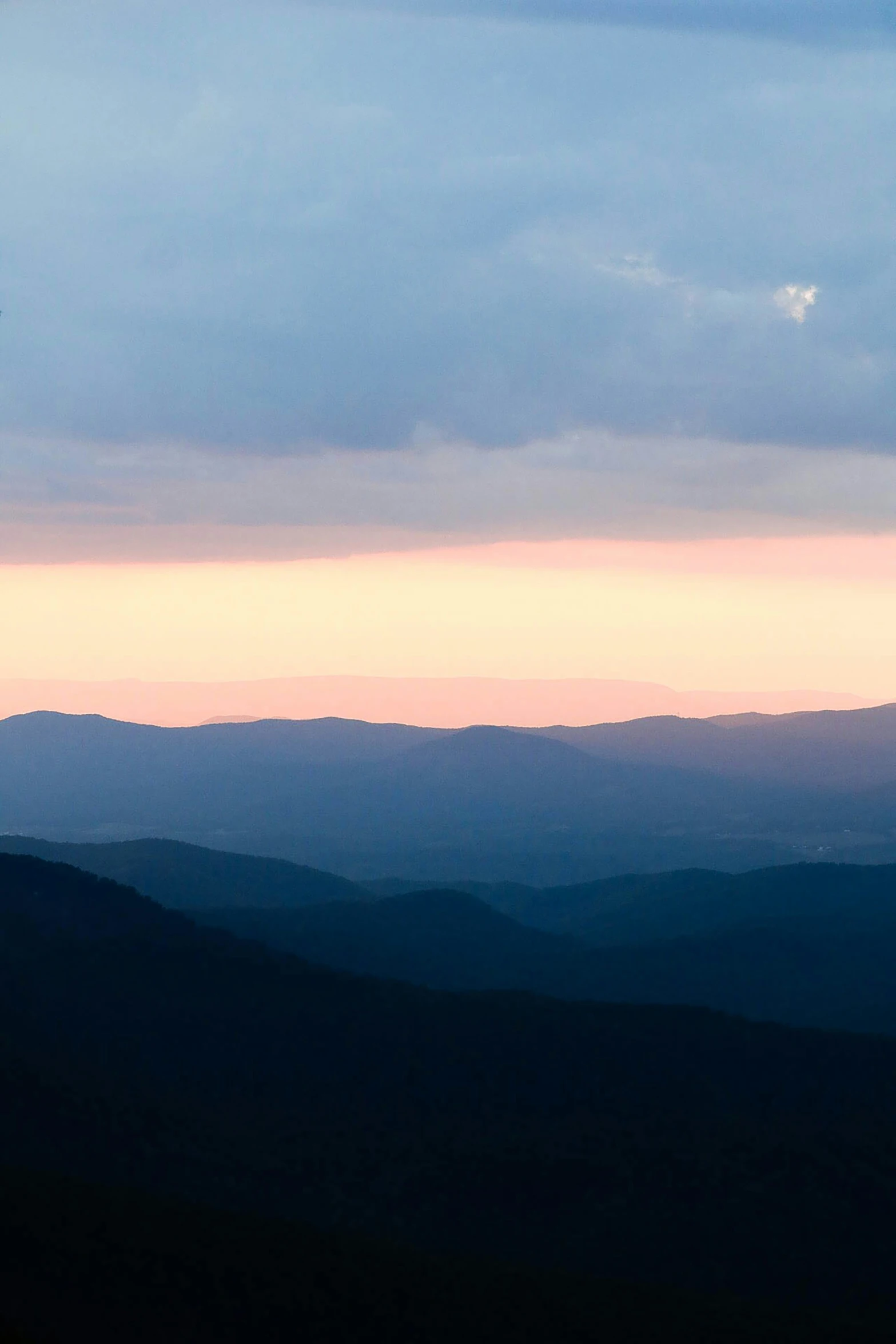 the mountains are blue, while the sky is pink and yellow