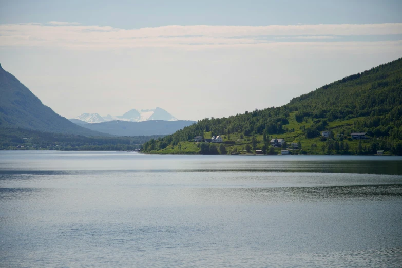 a lake with mountains and houses in the distance