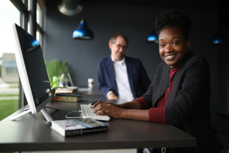 two people sit at a table working on computers