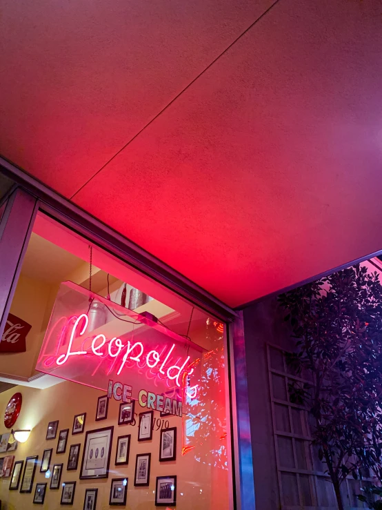 a red neon sign on the side of a store front window