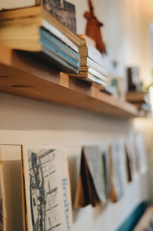 books on top of a wooden shelf next to a window