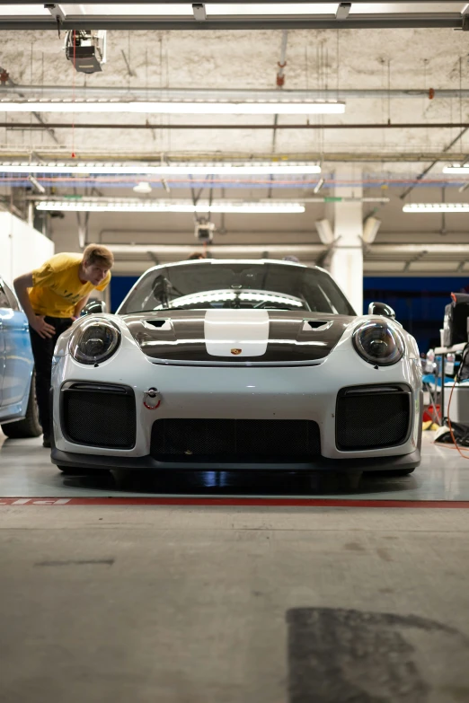 a man looking into a white car in a garage